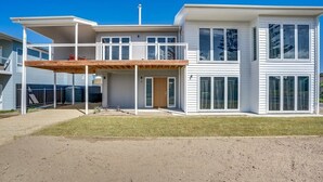 Et moderne hus med to etager, en overdækket terrasse, store vinduer og en synlig skorsten.