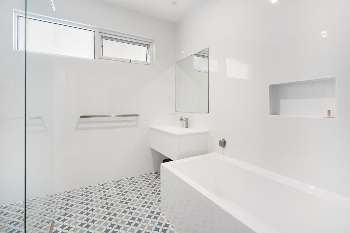 A modern bathroom with a bathtub, a glass shower enclosure, and a white sink.