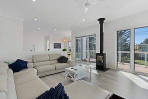 A modern living room with a sofa, coffee table, and a fireplace. - 5 Tabernacle Rd Encounter Bay-Electric CarCharging (Encounter Bay)