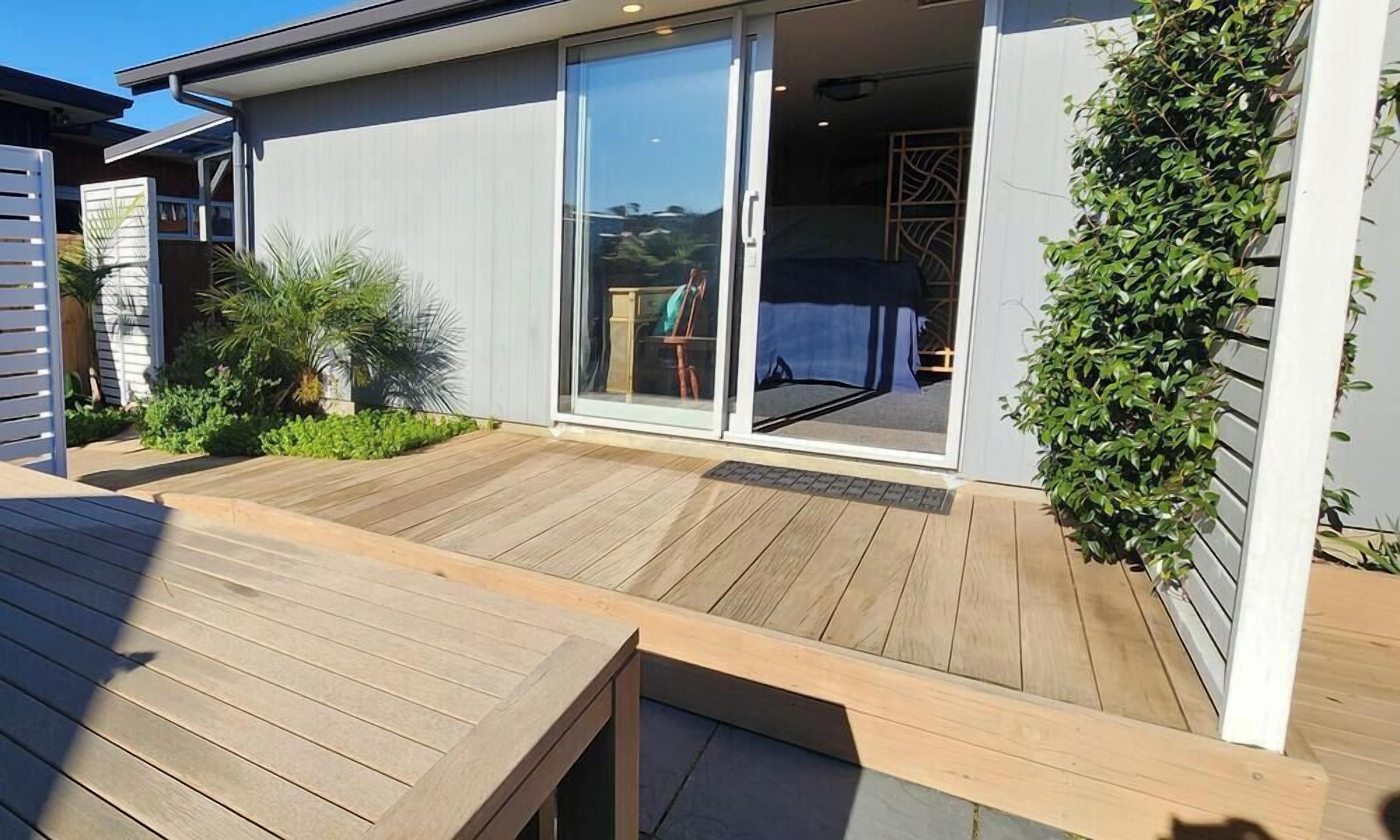 Una terraza de madera con un amplio ventanal corredizo que da a un patio cubierto.