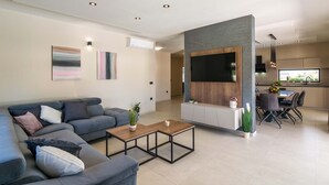Un soggiorno moderno con un divano grigio, un tavolino da caffè e una TV montata su una parete grigia.