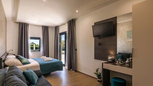 Una moderna camera d'hotel con un letto, una poltrona, una TV e una scrivania.