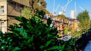 A row of terraced houses with a river and cranes in the background. - Stylish One Bedroom Flat in Kensingston, London (London)