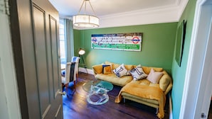 A living room with a green wall, a yellow sofa, and a glass coffee table. - Stylish One Bedroom Flat in Kensingston, London (London)