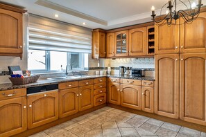 Kitchen features a large window, sink, and dishwasher, with a chandelier above the sink.
