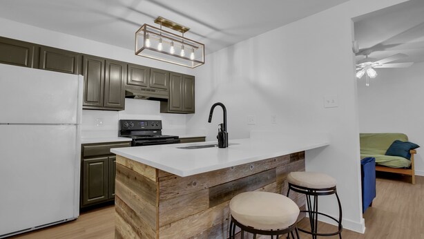 A modern kitchen with a white island, wooden accents, and bar stools. - Condo near downtown Austin, close to Town Lake! (Austin)