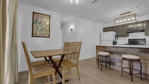 A modern kitchen with wooden cabinets, a dining table with chairs, and a bar area with stools. - Condo near downtown Austin, close to Town Lake! (Austin)