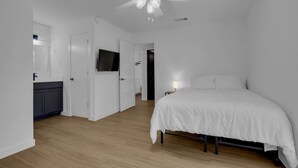 A bedroom with a bed, a ceiling fan, a TV, and a door leading to another room. - Condo near downtown Austin, close to Town Lake! (Austin)