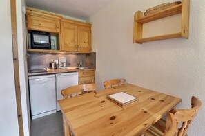 A compact kitchen with wooden cabinets, a microwave, a coffee maker, and a dishwasher. - 250m from ski slopes, 4th floor, balcony, 26m², Méribel-Mottaret (Méribel - Les Allues)