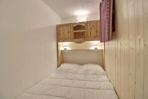 A single bed with a headboard, wooden paneling on the walls, and a small shelf above the bed. - 250m from ski slopes, 4th floor, balcony, 26m², Méribel-Mottaret (Méribel - Les Allues)