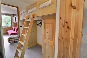 A room with a bunk bed, a ladder, a pink sofa, and a plaid chair. - 250m from ski slopes, 4th floor, balcony, 26m², Méribel-Mottaret (Méribel - Les Allues)