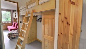 A room with a bunk bed, a ladder, a pink sofa, and a plaid chair. - 250m from ski slopes, 4th floor, balcony, 26m², Méribel-Mottaret (Méribel - Les Allues)