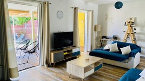 Una sala de estar moderna con televisor, sofá, mesa de centro y un balcón con sillas.
