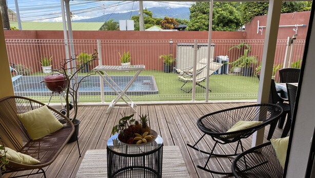 Un patio techado con sillas de mimbre, una mesa y una parrilla.