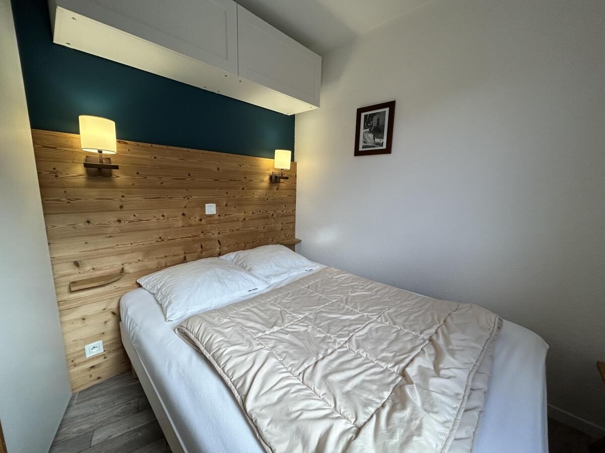 Una camera da letto con una testiera in legno, un letto con biancheria bianca e due lampade a parete.