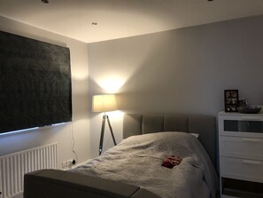 Cozy retreat with a comfortable bed, floor lamp, and dresser.