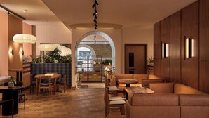 A modern interior with a wooden floor, leather seating, and a central archway leading to a bar area. - Sir Devonshire Square Hotel, part of Sircle Collection (London)