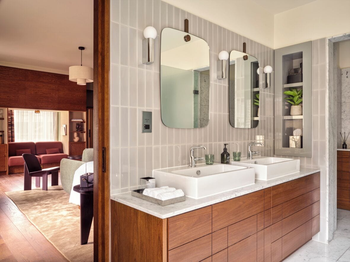 A modern bathroom with two sinks, a large mirror, and a wooden vanity.
