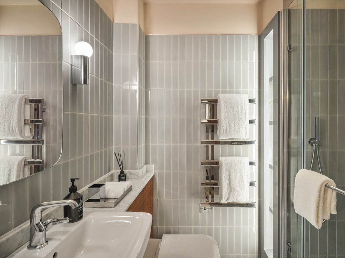 A modern bathroom with a large mirror, a sink, a toilet, and a glass shower enclosure.