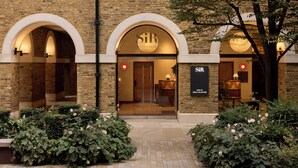 A brick building with arched entrances and a sign reading "SIR" on the facade. - Sir Devonshire Square Hotel, part of Sircle Collection (London)