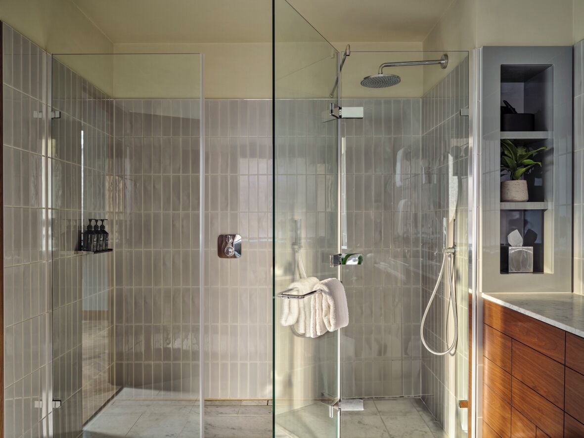 Une salle de bain moderne avec une douche à parois de verre, un meuble-lavabo en bois et une petite étagère contenant des articles de toilette.