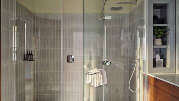 Une salle de bain moderne avec une douche à parois de verre, un meuble-lavabo en bois et une petite étagère contenant des articles de toilette.