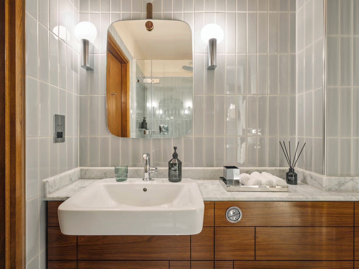 A bathroom with a large mirror, a sink, and a vanity with a wooden cabinet.