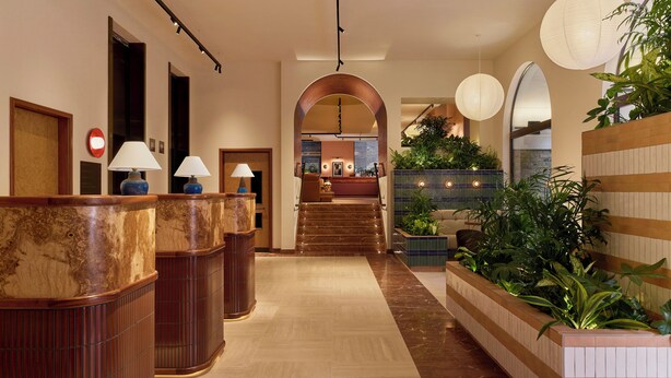 A hotel lobby with a marble floor, wooden reception desk, and a staircase leading to the upper floor. - Sir Devonshire Square Hotel, part of Sircle Collection (London)