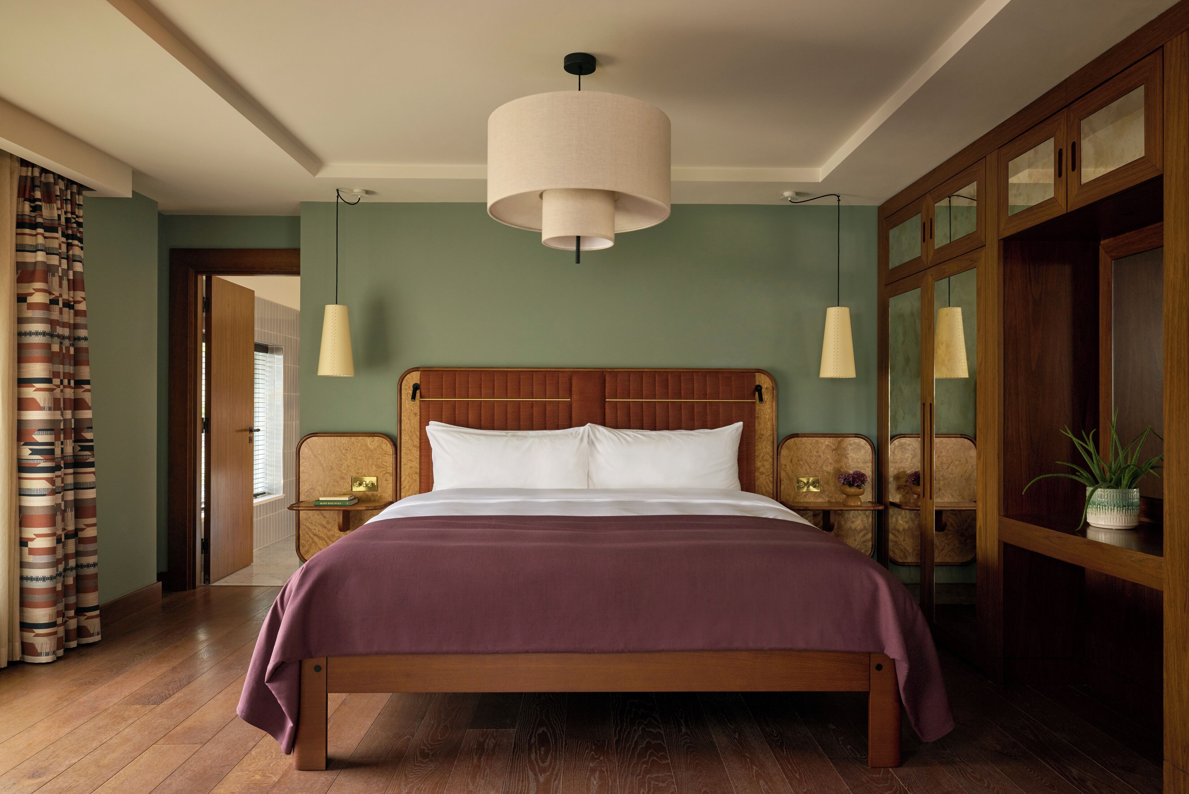 A bedroom with a wooden bed, a large hanging light fixture, and a view of the hallway.