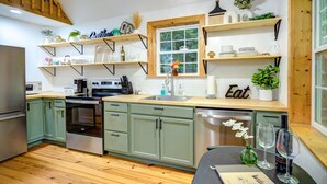 A modern kitchen with green cabinets, a wooden countertop, and a window with a view. - Visit #mytreetophideaway located in Banner Elk, NC, nestled high in the trees.  (Banner Elk)