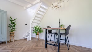 A dining area with a wooden table and chairs, a chandelier, and a staircase leading to an upper level. - Neu:wunderschöne und Preiswerte Ferienwohnung mit Jedem Komfort (Westhoek)