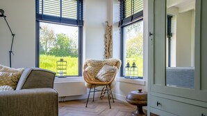 A room with a large window, a wicker chair, a wooden floor, and a cabinet. - Neu:wunderschöne und Preiswerte Ferienwohnung mit Jedem Komfort (Westhoek)