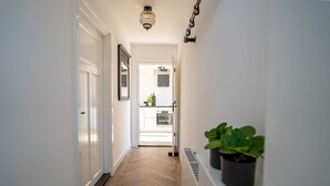 A hallway with a wooden floor, white walls, a door, a potted plant, and a ceiling light fixture. - Neu:wunderschöne und Preiswerte Ferienwohnung mit Jedem Komfort (Westhoek)