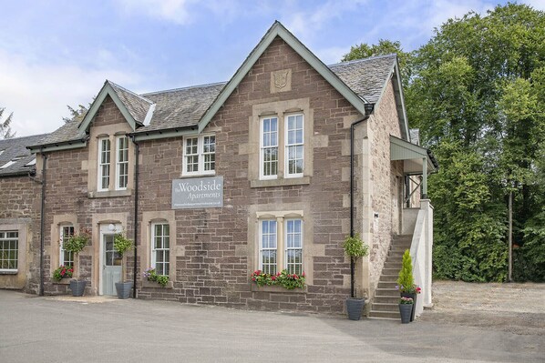 A stone building with a sign reading "The Woodside Apartments." - The Woodside Apartments (Doune)
