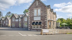 A traditional stone building with multiple windows and a sign for 'The Woodside' pub. - The Woodside Apartments (Doune)