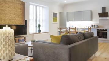 Una sala de estar moderna con un sofá gris, una lámpara y un comedor con mesa y sillas.