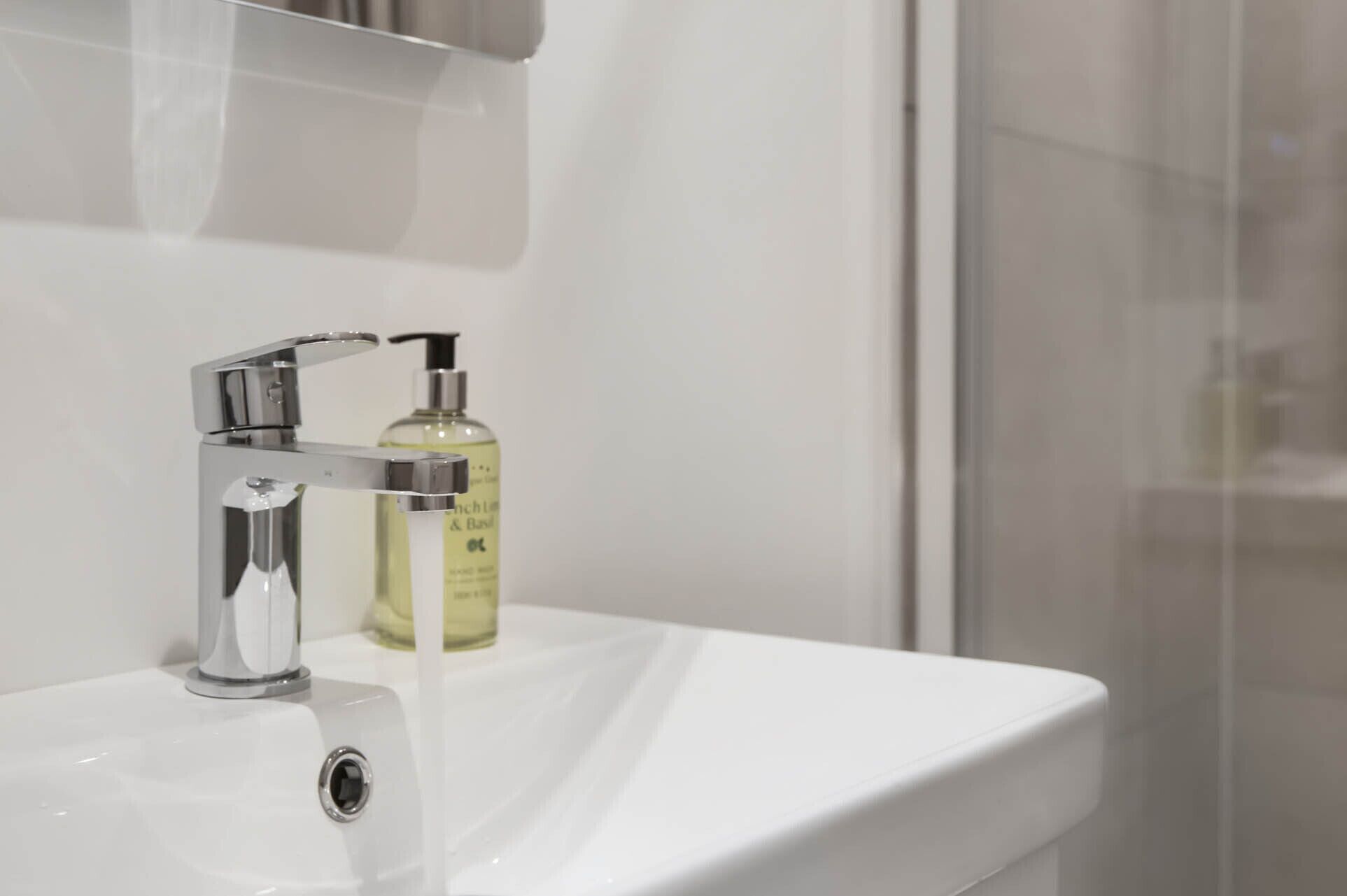 Un lavabo de salle de bain avec un robinet chromé et un flacon de savon liquide.