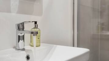 Un lavabo de salle de bain avec un robinet chromé et un flacon de savon liquide.