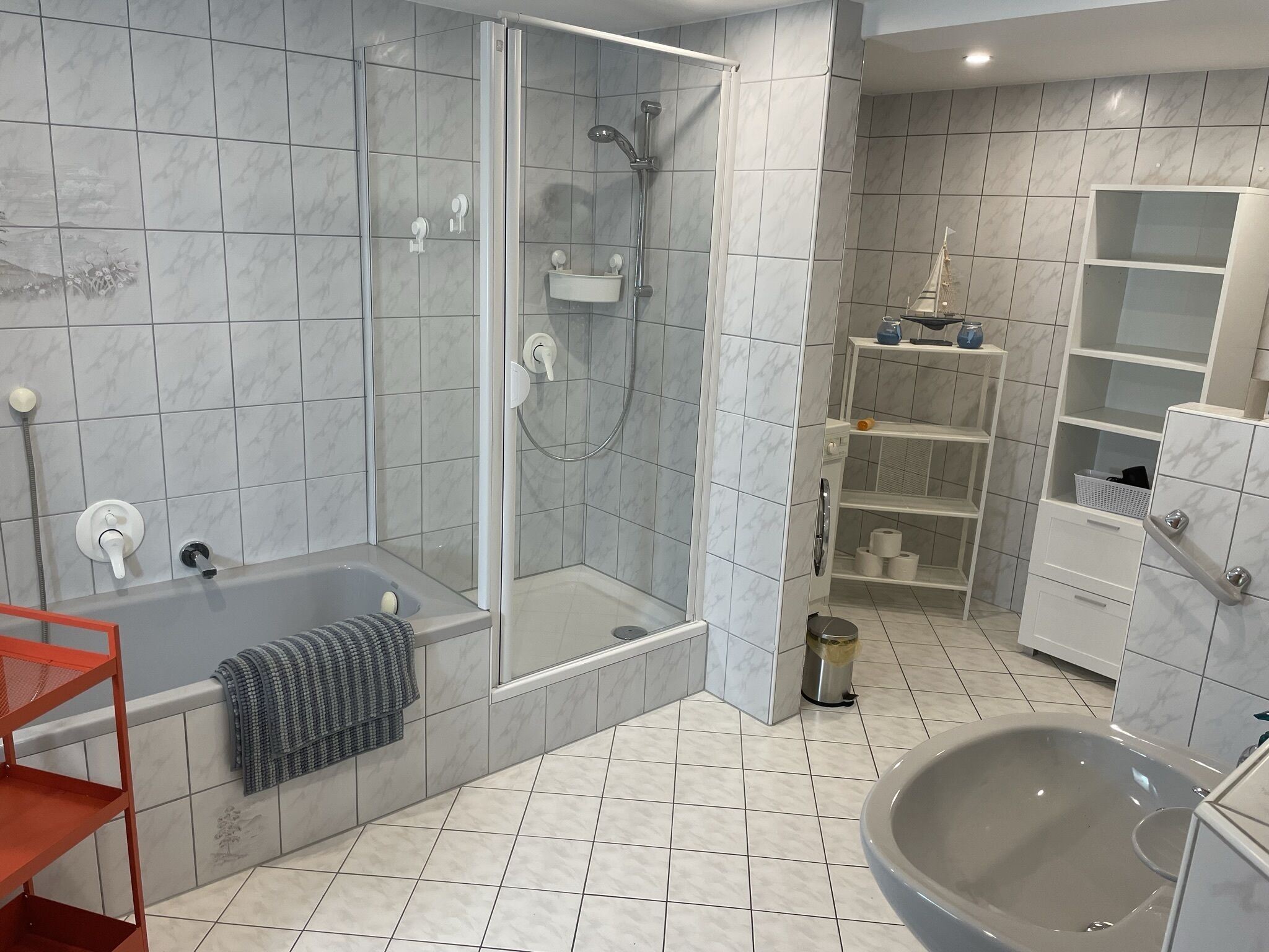 Et moderne badeværelse med et glasafskærmet brusebad, et fristående badekar og en stor vask.
