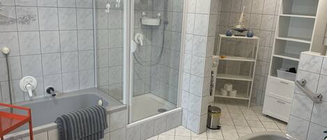 Et moderne badeværelse med et glasafskærmet brusebad, et fristående badekar og en stor vask.