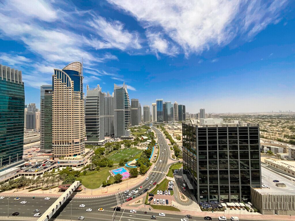 Un paysage urbain avec des immeubles modernes de grande hauteur, une route sinueuse et un espace vert aménagé en parc.