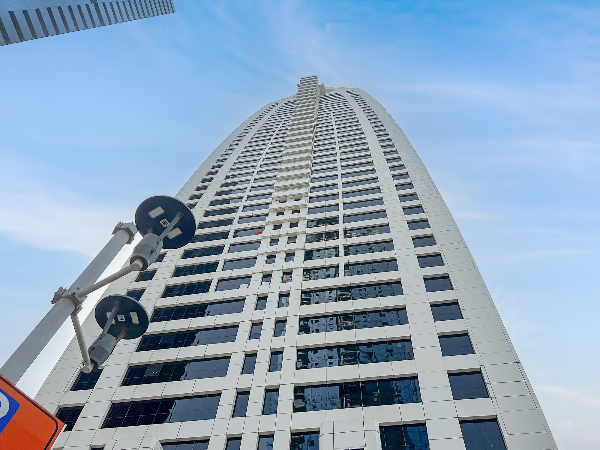Un edificio alto y moderno con una fachada de ventanas en forma de cuadrícula y una estructura de antena destacada a la izquierda.