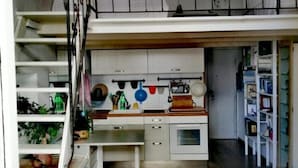 Eine kleine Küche mit weißen Schränken, einer Holz Arbeitsplatte und einem Essbereich.