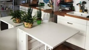 Eine moderne Küche mit weißen Schränken, einer Holzausziehtheke und einer eingebauten Kochinsel mit Stauraum.