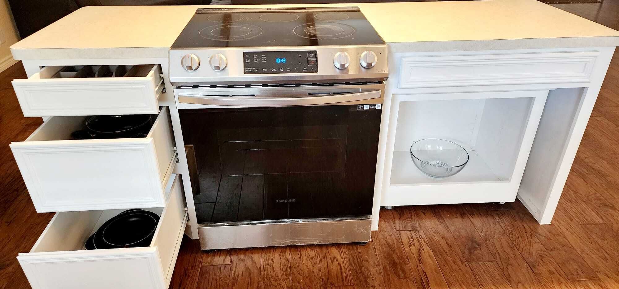 A kitchen with a built-in oven and microwave, white cabinetry, and a wooden floor.