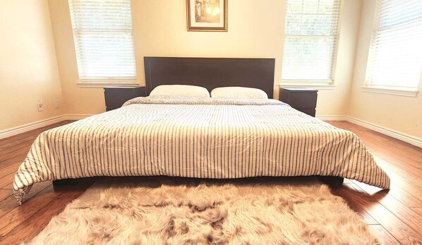 A bedroom with a large bed, a dark headboard, and a fluffy rug.