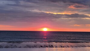 A sunset over the ocean with waves approaching the shore. - Amazing Sunsets & Luxury - Soundfront Pet Friendly Oasis w/ Elevator & Hot Tub (Kitty Hawk)
