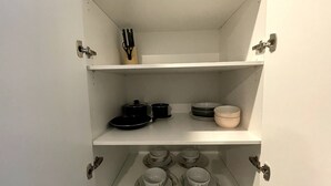 A white cabinet with three shelves, each containing kitchenware. - Specious apartment in Kingston, centrally located place. (Kingston)