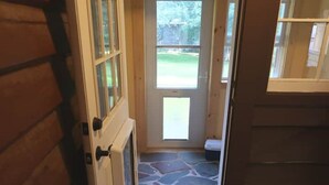 A wooden door with a glass panel, leading to a stone-tiled entrance area. - Dog Friendly, located Between Lake Placid and Saranac Lake with pontoon rentals (Ray Brook)