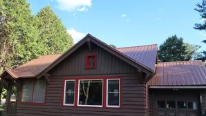 A wooden cabin with a red roof and two garage doors. - Dog Friendly, located Between Lake Placid and Saranac Lake with pontoon rentals (Ray Brook)
